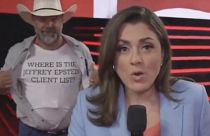 Protestocu, üzerinde "Jeffrey Epstein'in müşteri listesi nerede?" yazılı tişörtünü kadraja gösteriyor (Ekran görüntüsü CNN'den alınmıştır)