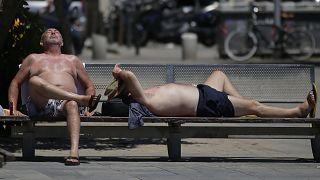Dos hombres disfrutan del sol en la playa de la Barceloneta en Barcelona, ​​España, el martes 13 de junio de 2017.