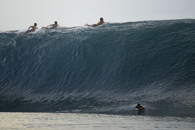 Los surfistas reman sobre la cima de una ola en Teahupo'o, Tahití, Polinesia Francesa.