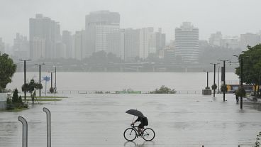 Um homem anda de bicicleta no meio de fortes chuvas num parque público ao longo do rio Han em Seul, Coreia do Sul, quinta-feira, 18 de julho de 2024. AP Photo/Ahn Young-joon)