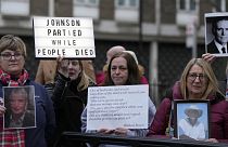 Protesters show pictures of COVID victims and placards outside Dorland House as former PM Boris Johnson testifies at Britain's COVID-19 public inquiry in December 2023.