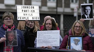 Protesters show pictures of COVID victims and placards outside Dorland House as former PM Boris Johnson testifies at Britain's COVID-19 public inquiry in December 2023.