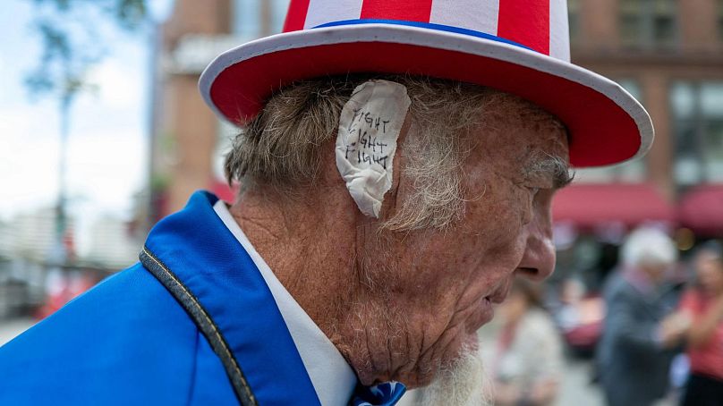 Trump supporter in Milwaukee wearing a bandage over his ear with the words "fight, fight, fight" 