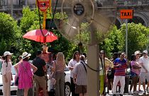 Des touristes attendent un bus sous le soleil à Milan, en Italie, le 16 juillet 2024.