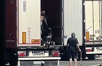 سائق شاحنة يضرب مهاجرات بالطرف المعدني لحزام الشحن أثناء خروجهن من الجزء الخلفي من شاحنته في محطة استراحة بالقرب من الحدود الفرنسية في فينتيميليا، الاثنين 15 يوليو 2024.