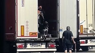 سائق شاحنة يضرب مهاجرات بالطرف المعدني لحزام الشحن أثناء خروجهن من الجزء الخلفي من شاحنته في محطة استراحة بالقرب من الحدود الفرنسية في فينتيميليا، الاثنين 15 يوليو 2024.