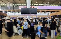 Utasok várakoznak a Berlin-Brandenburg repülőtér üres fekete kijelzőtáblájánál