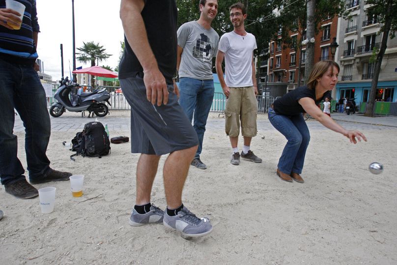 Uma parisiense atira uma bola de metal enquanto joga petanca com os seus amigos em Paris, sábado, 7 de agosto de 2010