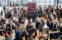 Passengers wait at Berlin Brandenburg Airport, Germany, after a widespread technology outage disrupted flights on 19 July 2024. 