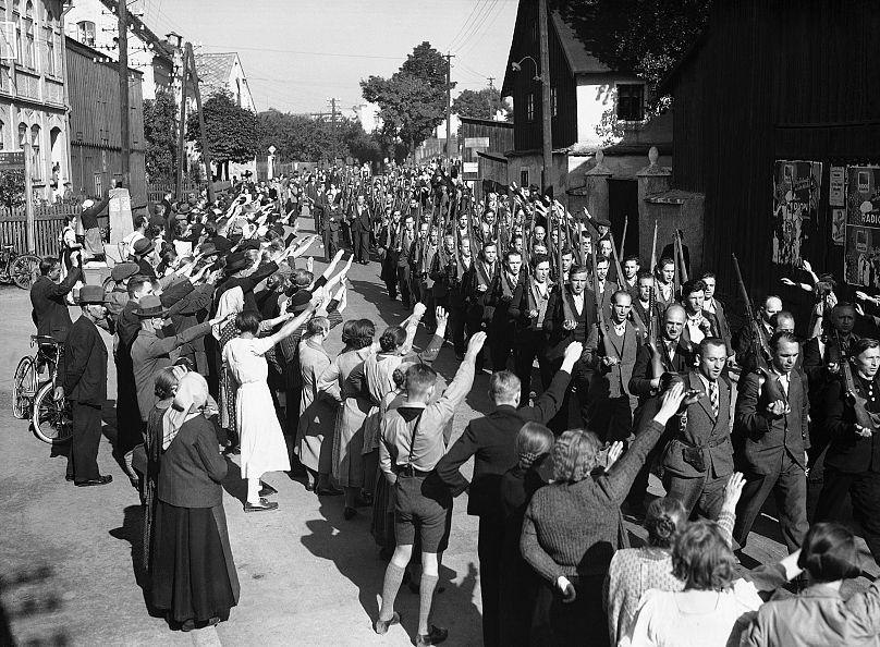 Sudeten Germans from the Free Corps receiving the Nazi salute as they pass through Haslow as they march back into Czechoslovakia on Sept. 22, 1938. 