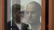 Wall Street Journal reporter Evan Gershkovich stands listening to the verdict in a glass cage in a courtroom in Yekaterinburg, 19 July 2024, FILE