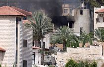 Dzsenín, 2024. július 5. Izraeli katonai járművek egy kigyulladt épület előtt a Ciszjordánia északi részén fekvő Dzsenín városában folytatott rajtaütés során 2024. július 5-én