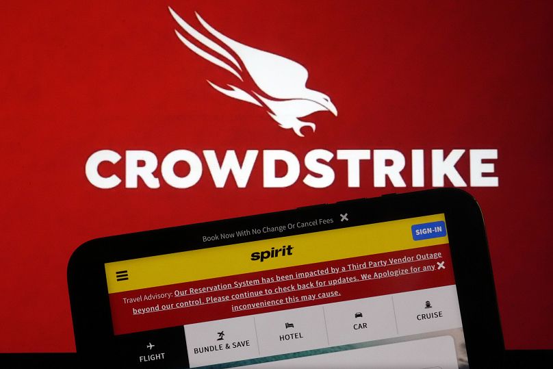 The logo for CrowdStrike and a Spirit Airlines webpage are shown on a computer screen and mobile phone screen in New York, July 19, 2024