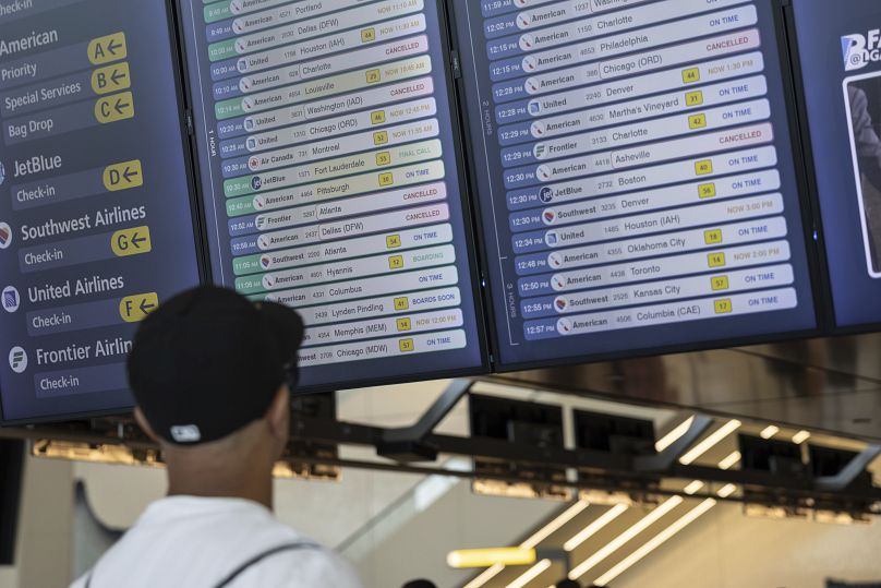 A person checks flight schedules on the screen at a departure floor of LaGuardia Airport in New York, July 19, 2024