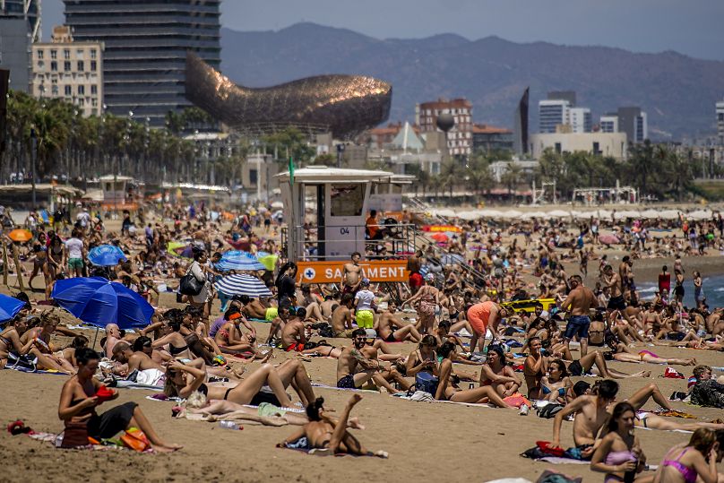 Des personnes prennent un bain de soleil sur la plage de Barcelone, le 9 juillet 2021.