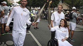 Basın ajansı fotoğrafçısı Christina Assi, sağda, Olimpiyat meşalesini birlikte tutuyor. Nicolas Payeur, solda, 21 Temmuz 2024 Pazar günü 2024 Yaz Olimpiyatlarında,