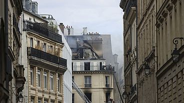Os bombeiros trabalham numa pequena rua após um incêndio num edifício de apartamentos, sábado, 20 de julho de 2024, no centro de Paris, França. (AP Photo/Thomas Padilla)