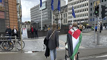  امرأة ترتدي العلم الفلسطيني بجانب مقر الاتحاد الأوروبي في بروكسل، الأحد، 26 مايو 2024. 