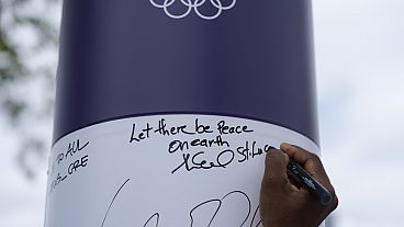 هيلينا رينيه إيمانويل من سانت لوسيا توقع على عمود أثناء تدشين جدار الهدنة الأولمبية في القرية الأولمبية في دورة الألعاب الأولمبية الصيفية 2024، الاثنين 22 يوليو 2024، في باريس