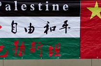 Filistin Büyükelçiliği önünde yapılan bir protesto sırasında "Özgür ve Barış" yazılı bir Filistin bayrağı, Çin ulusal bayrağının yanında asılı duruyor.