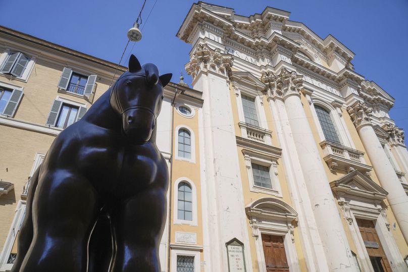 Fernando Botero's "Horse with Bridle" sculpture sits before the Saints Ambrogio and Carlo Basilica at Rome's Via del Corso