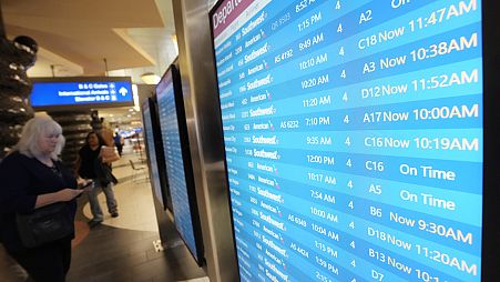 Passengers check a departures board at Phoenix Sky Harbor International Airport Friday, July 19, 2024, in Phoenix.