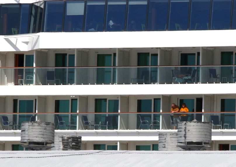 Deux personnes regardent depuis le navire de croisière Norwegian Jewel à Honolulu le lundi 23 mars 2020.