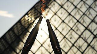 La torche olympique est vue lors d'un relais dans la cour du musée du Louvre dimanche 14 juillet 2024 à Paris.