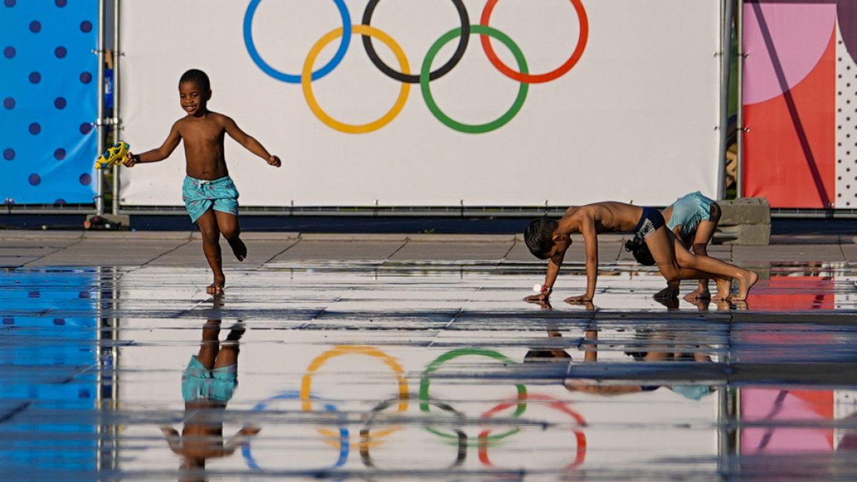 Des enfants s'amusent dans une fontaine près du logo des Jeux olympiques 2024, mardi 23 juillet, à Nice qui accueillera six matchs de foot.