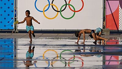 Des enfants s'amusent dans une fontaine près du logo des Jeux olympiques 2024, mardi 23 juillet, à Nice qui accueillera six matchs de foot.
