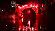 Ένας δύτης που κρατά πυρσούς πηδάει από την Παλιά Γέφυρα κατά τη διάρκεια νυχτερινής επίδειξης, μέρος του 456ου παραδοσιακού ετήσιου διαγωνισμού καταδύσεων στο Μόσταρ της Βοσνίας, Κυριακή 31 Ιουλίου 2024. 