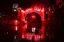 A diver holding torches jumps from the Old Bridge during a night show, part of the 456th traditional annual high diving competition in Mostar, Bosnia, Sunday, July 31, 2024. 