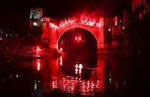 Um mergulhador com tochas salta da Ponte Velha durante um espetáculo noturno em Mostar, na Bósnia, no domingo, 31 de julho de 2024. 