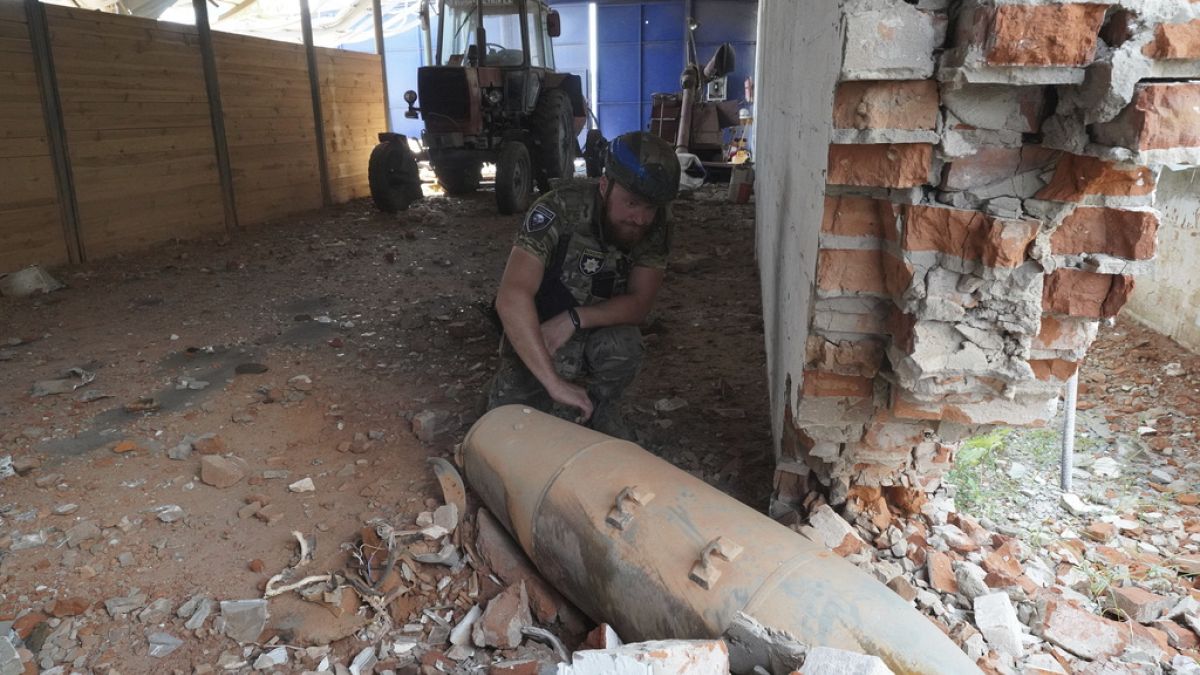 Un agente di polizia ispeziona una bomba inesplosa di 250 chilogrammi dopo un attacco aereo russo al magazzino della fattoria di Bilyi Kolodiaz, nella regione di Kharkiv, Ucraina, giovedì 11 luglio.