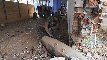 ضابط شرطة يتفقد قنبلة غير منفجرة تزن 250 كيلوغرامًا (550 رطلاً) بعد غارة جوية روسية على مستودع مزرعة في بيلي كولودياز، منطقة خاركوف، أوكرانيا، الخميس 11 يوليو.