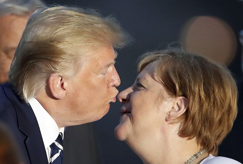 President Donald Trump kisses German Chancellor Angela Merkel during the G7 family photo Sunday, Aug. 25, 2019 in Biarritz