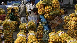  Un operaio trasporta sacchi di arance in un mercato all'ingrosso di frutta a Lahore, in Pakistan, il 1° dicembre 2021...