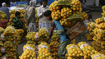  A laborer carries sacks of oranges in a wholesale fruit market in Lahore, Pakistan, on Dec. 1, 2021...