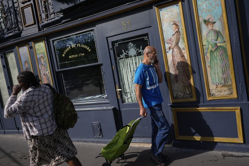 People walk past a restaurant decorated with artwork, ahead of the 2024 Summer Olympics in Paris, July 2024