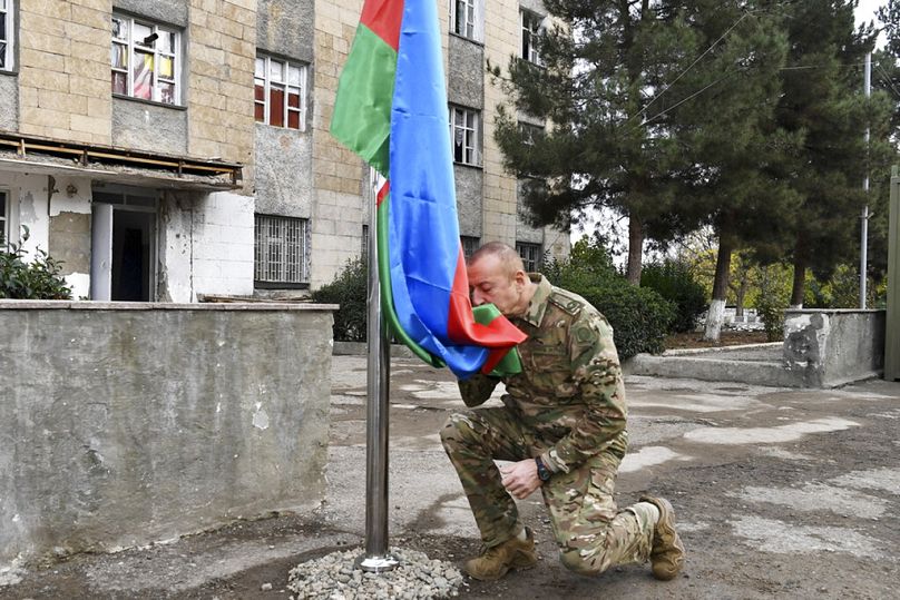 Ilham Alijev azeri elnök megcsókolja a nemzeti zászlót a visszafoglalt területen, 2020