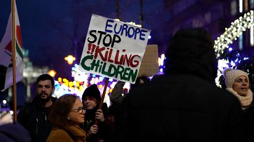 Bir protestocu Brüksel'deki AB zirvesi dışında Gazze'de ateşkes çağrısı yapan bir gösteri sırasında bir pankart tutuyor.