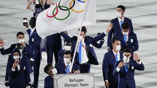 Yusra Mardini and Tachlowini Gabriyesos, of the Refugee Olympic Team, carry the Olympic flag during the opening ceremony in the Olympic Stadium at the 2020 Summer Olympics.