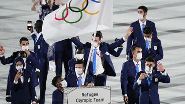 Yusra Mardini and Tachlowini Gabriyesos, of the Refugee Olympic Team, carry the Olympic flag during the opening ceremony in the Olympic Stadium at the 2020 Summer Olympics.