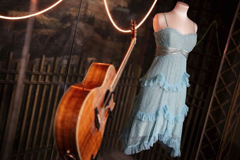 A guitar and stage costume from previous concert tours are displayed at the 'Taylor Swift Songbook Trail Exhibition' at the Victoria & Albert Museum.