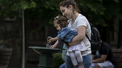 Madre e figlia a una fontanella in un giorno di canicola