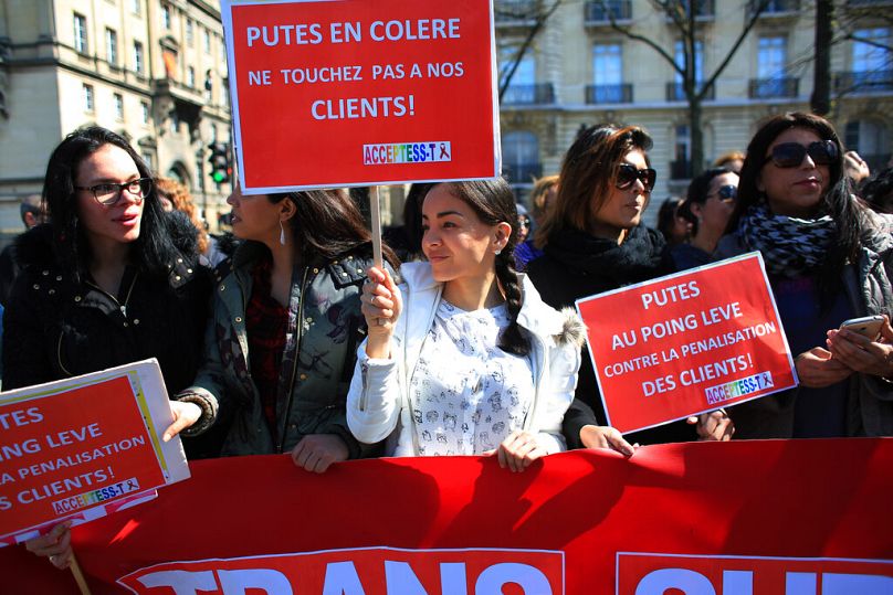 Sex workers hold signs reading 'Prostitutes are angry. Don't touch to our customers' during a protest against new bill against prostitution and sex trafficking, in Paris, Wedn