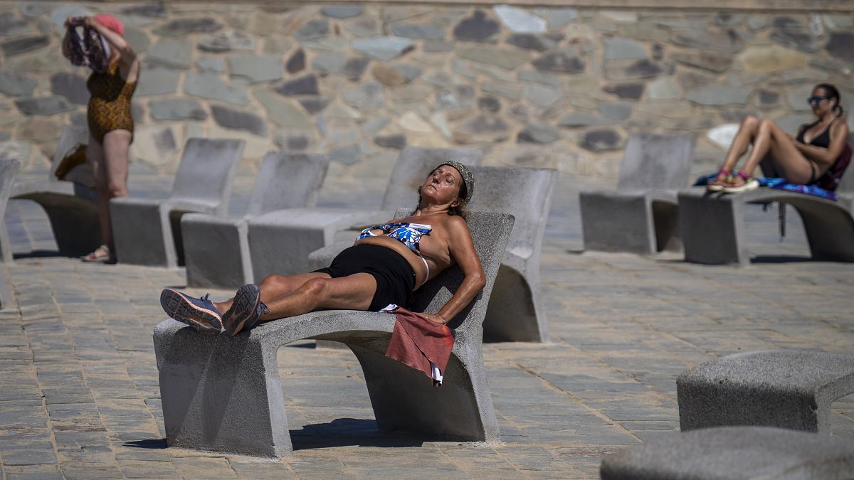 People sunbathe on a promenade in Barcelona, Spain, Wednesday, July 24, 2024. 