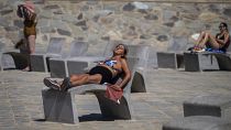 People sunbathe on a promenade in Barcelona, Spain, Wednesday, July 24, 2024. 