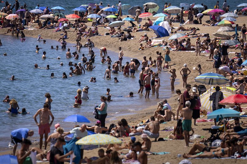 Bathers cool off in the water while others sunbathe on a Barcelona beach.