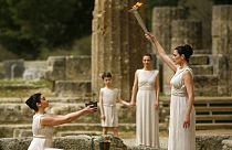 ماریا نافپلیوتو، هنرپیشه یونانی، در نقش یک کاهن اعظم، شعله المپیک را در نزدیکی معبد هرا در المپیای باستانی می‌افروزد، سال ۲۰۰۸ میلادی.